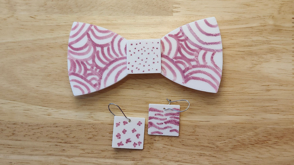 Bespoke It Yourself/Solid White Bow Bundle decorated sample including Square Button Cover and Blank Bow with matching Square earrings. 3D printed then hand colored by the customer for use as a bow tie, button cover, necklace, pin, hat pin, lapel pin and so much more.