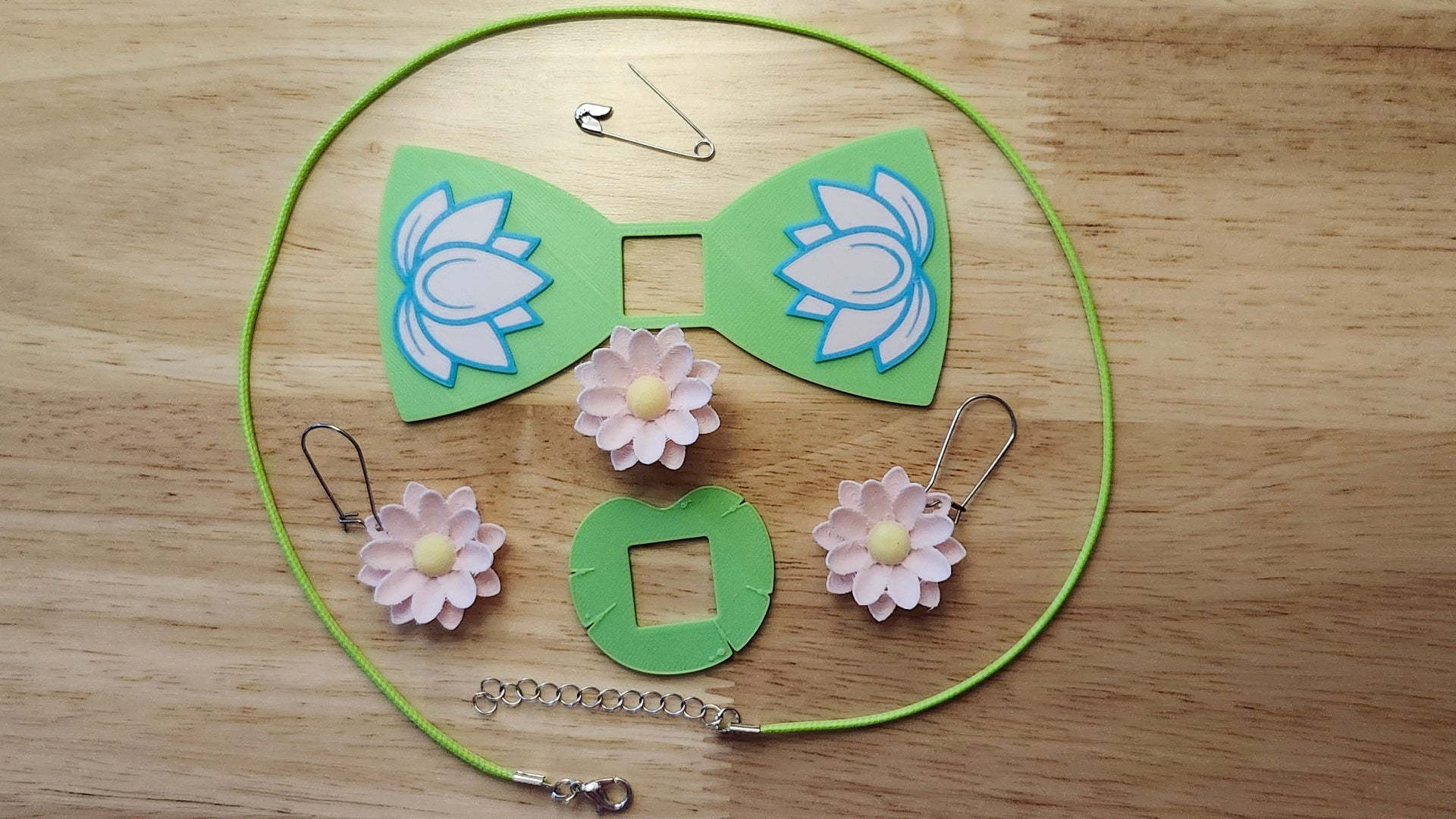 Lotus Bow Bundle including Lotus Flower Button Cover, Lotus Bow, Lily Pad Back, matching Lotus Flower earrings, a safety pin and silvery necklace. 3D printed for use as a bow tie, button cover, necklace, pin, hat pin, lapel pin and so much more.