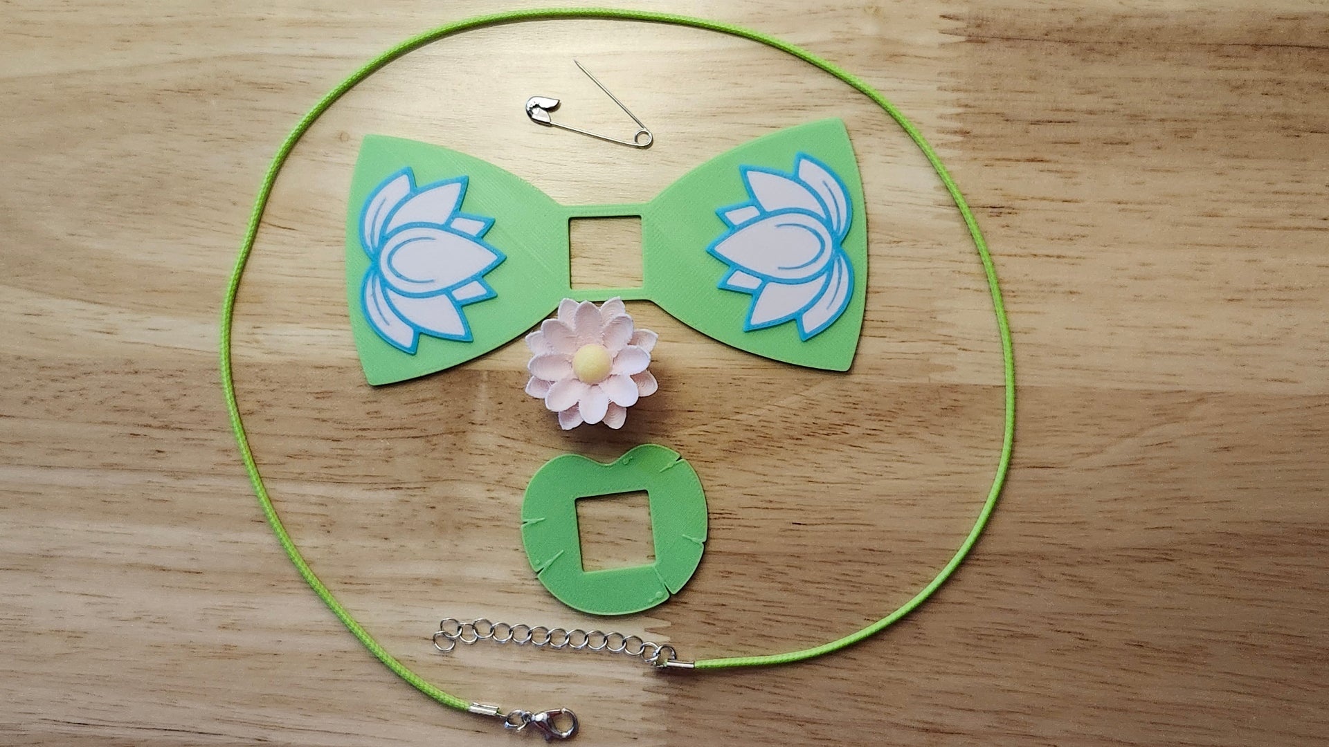 Lotus Bow Bundle including Lotus Flower Button Cover, Lotus Bow, Lily Pad Back, a safety pin and silvery necklace. 3D printed for use as a bow tie, button cover, necklace, pin, hat pin, lapel pin and so much more.