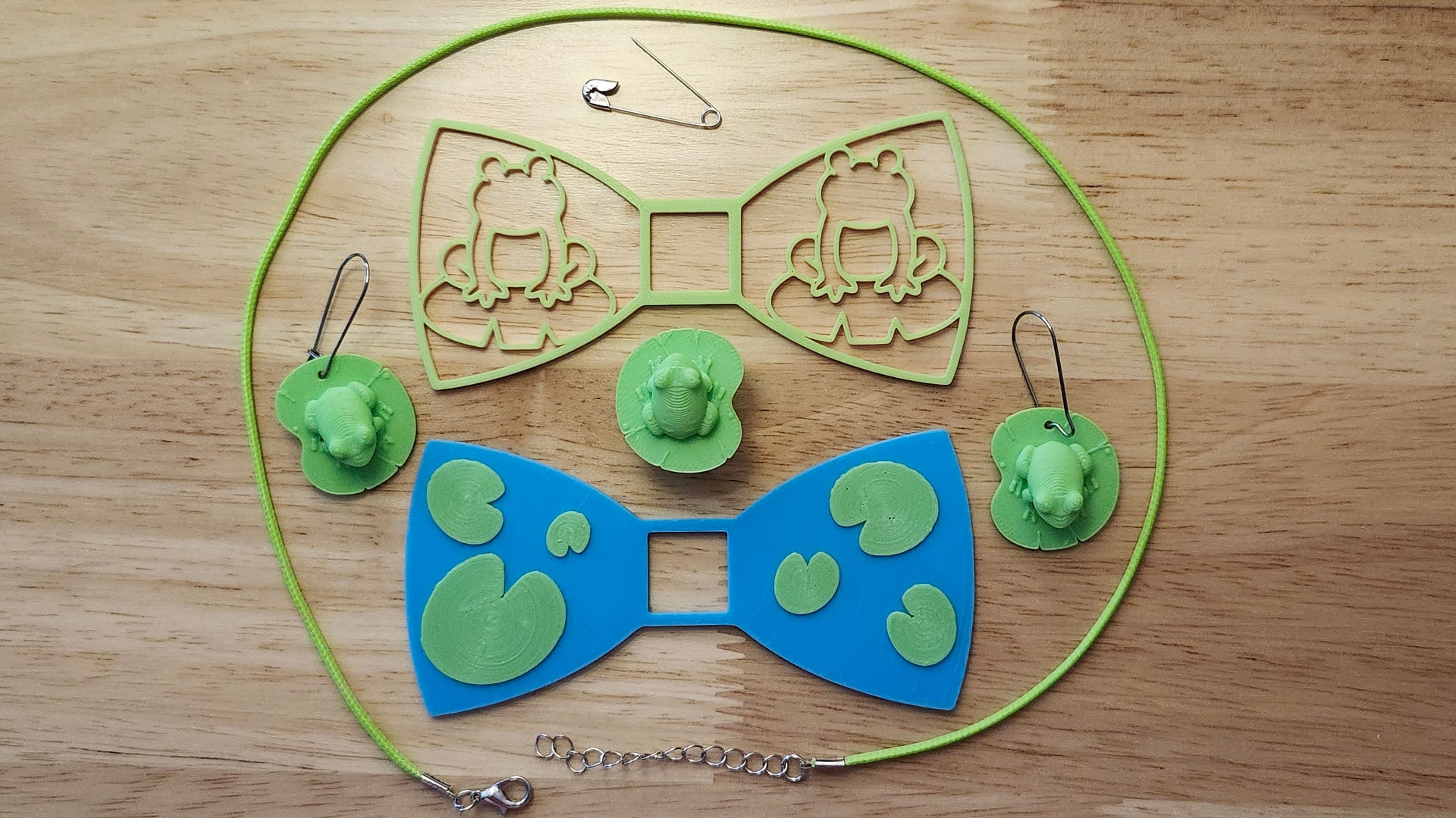 Frog Bow Bundle including Frog Button Cover, Lily Pad Bow, Frog Outline Bow, matching Frog on Lily Pad earrings, a safety pin and silvery necklace. 3D printed for use as a bow tie, button cover, necklace, pin, hat pin, lapel pin and so much more. 