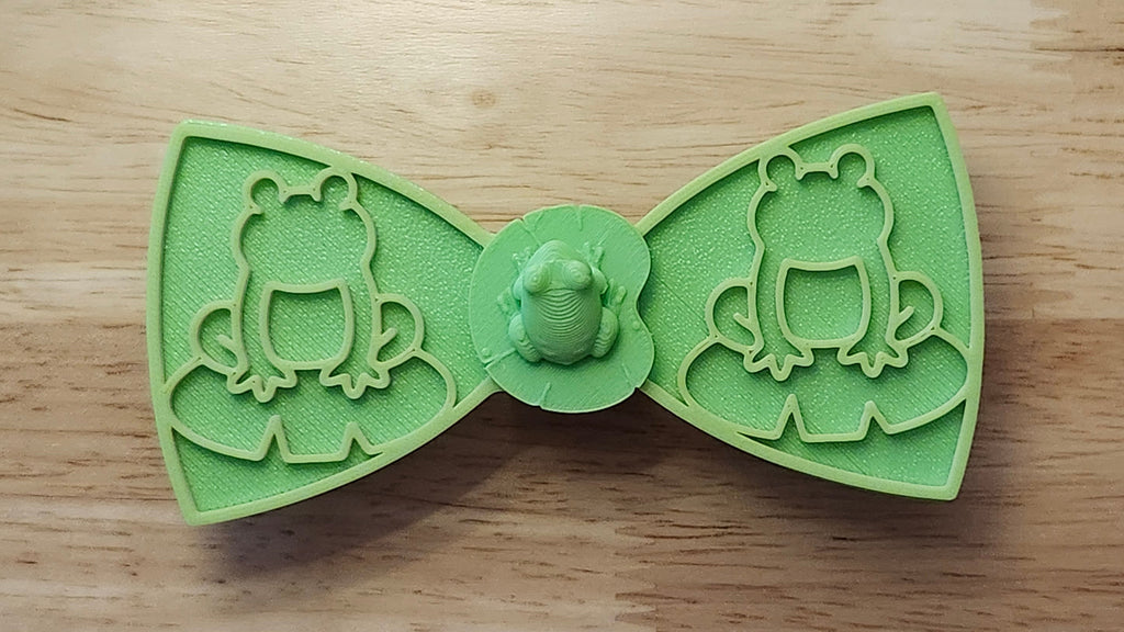 Frog Button Cover with Frog Outline Bow (green side) and Lotus Bow (reverse side). 3D printed for use as a bow tie, button cover, necklace, pin, hat pin, lapel pin and so much more. 