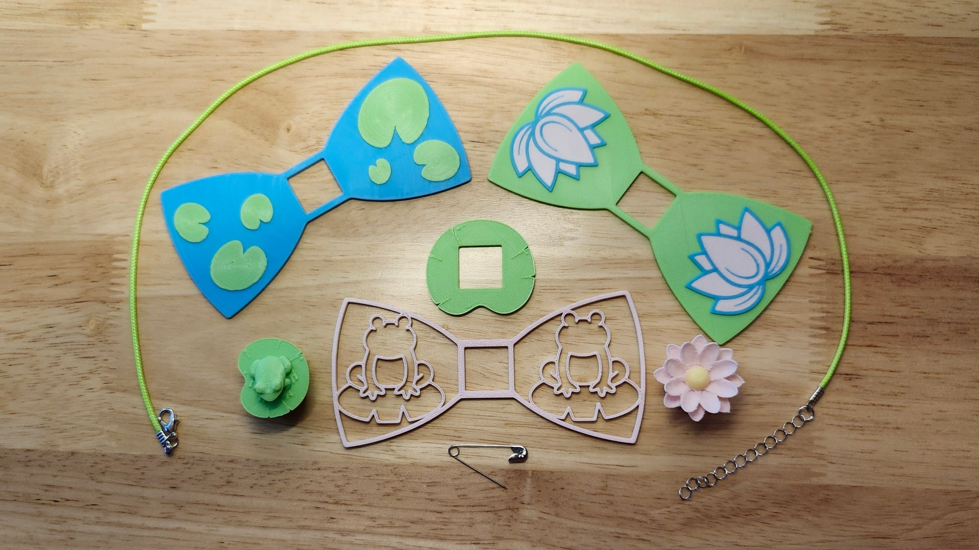 Lily Pond Bow Big Bundle including Frog Button Cover, Lily Pad Bow, Frog Outline Bow, the Lotus Flower Button Cover, Lotus Bow, Lily Pad Back, a safety pin and silvery necklace. 3D printed for use as a bow tie, button cover, necklace, pin, hat pin, lapel pin and so much more. 
