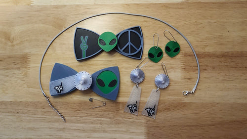 Aliens Are Real Bow Big Bundle including UFO Button Cover, Alien Head Bow, Cow Beaming Back, Alien Head Button Cover, Alien Peace Hand Bow, Peace Sign Bow, matching UFO Beaming Up Cow and Alien Head earrings 2 safety pins and an 18 inch gray necklace. 3D printed for use as a bow tie, button cover, necklace, pin, hat pin, lapel pin and so much more. 