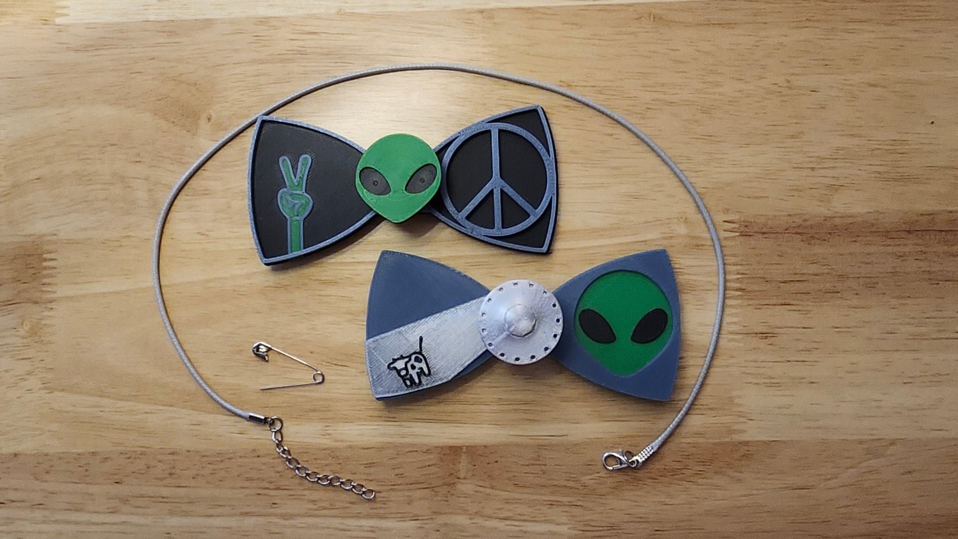 Aliens Are Real Bow Big Bundle including UFO Button Cover, Alien Head Bow, Cow Beaming Back, Alien Head Button Cover, Alien Peace Hand Bow, Peace Sign Bow, 2 safety pins and an 18 inch gray necklace. 3D printed for use as a bow tie, button cover, necklace, pin, hat pin, lapel pin and so much more. 
