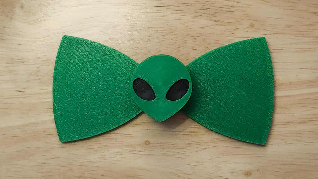 Alien Head Button Cover with Alien Head Bow (reverse side shown). 3D printed for use as a bow tie, button cover, necklace, pin, hat pin, lapel pin and so much more.