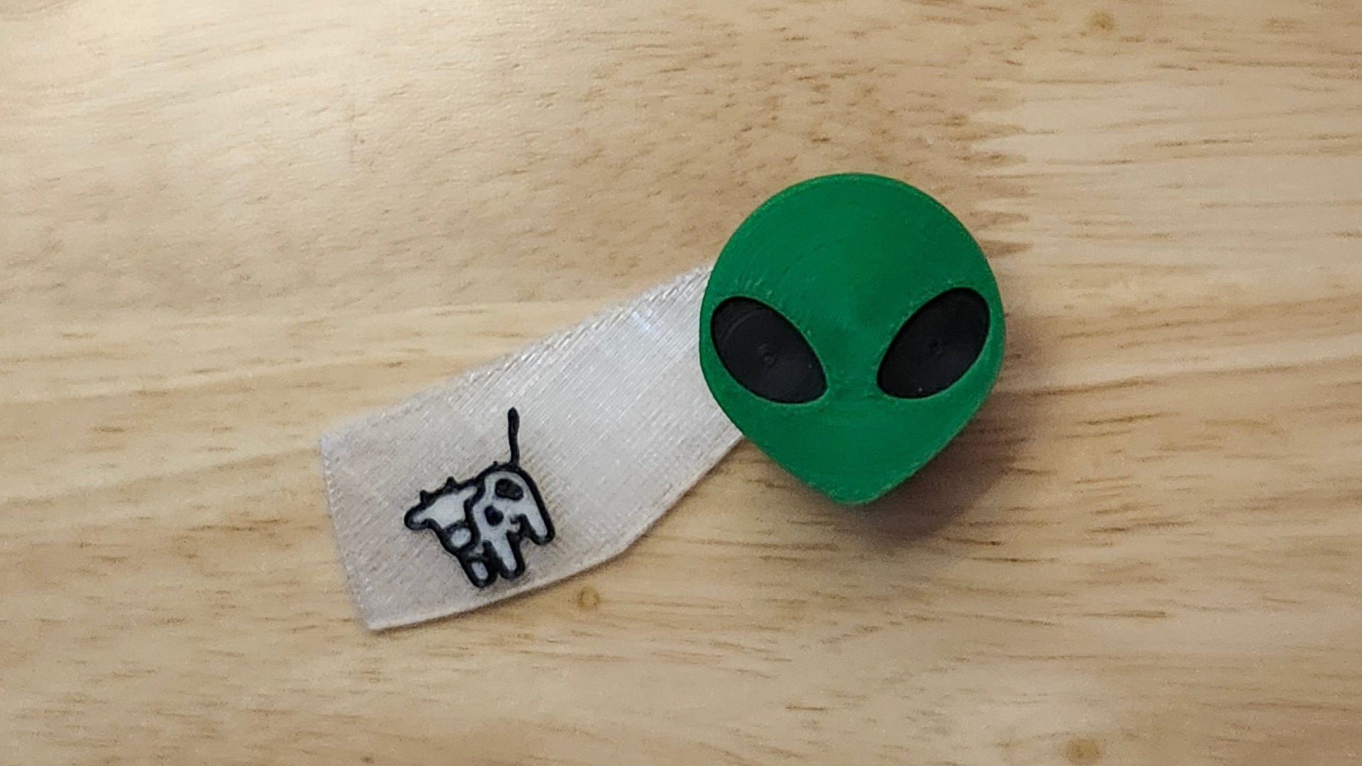 Alien Head Button Cover with Cow Beaming Back. 3D printed for use as a bow tie, button cover, necklace, pin, hat pin, lapel pin and so much more.