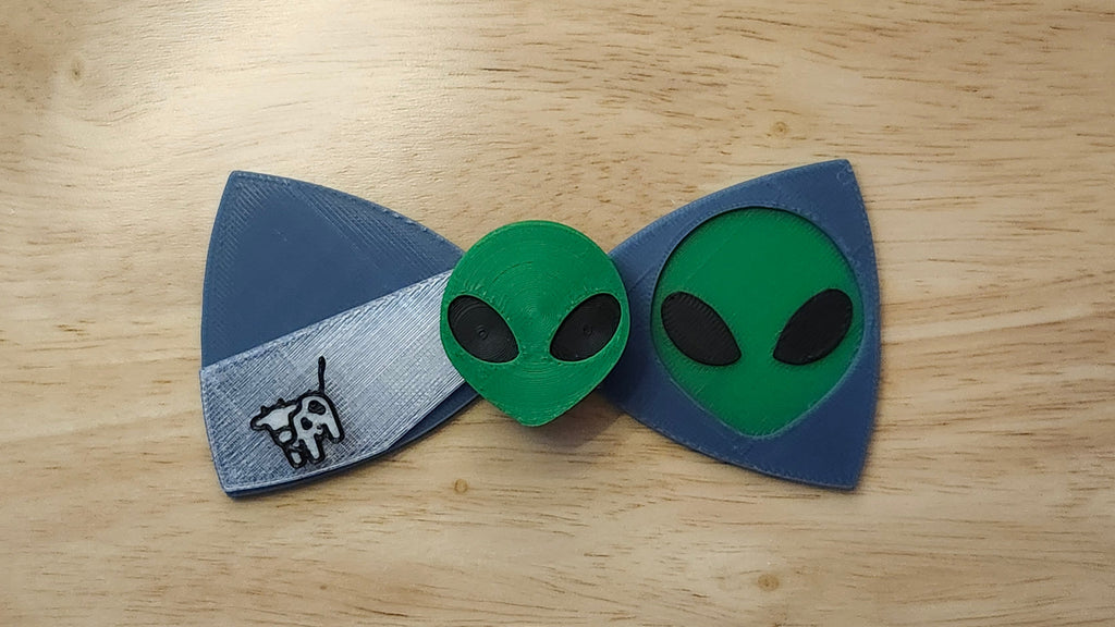 Alien Head Button Cover with Alien Head Bow and Cow Beaming Back. 3D printed for use as a bow tie, button cover, necklace, pin, hat pin, lapel pin and so much more.