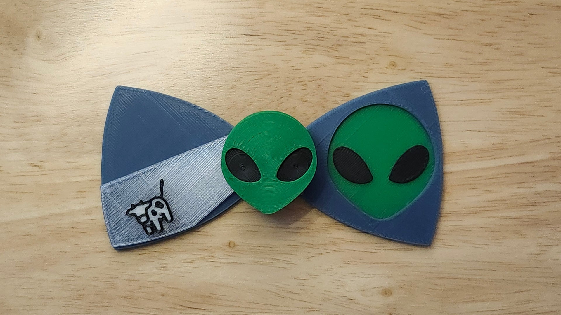 Alien Head Button Cover with Alien Head Bow and Cow Beaming Back. 3D printed for use as a bow tie, button cover, necklace, pin, hat pin, lapel pin and so much more.