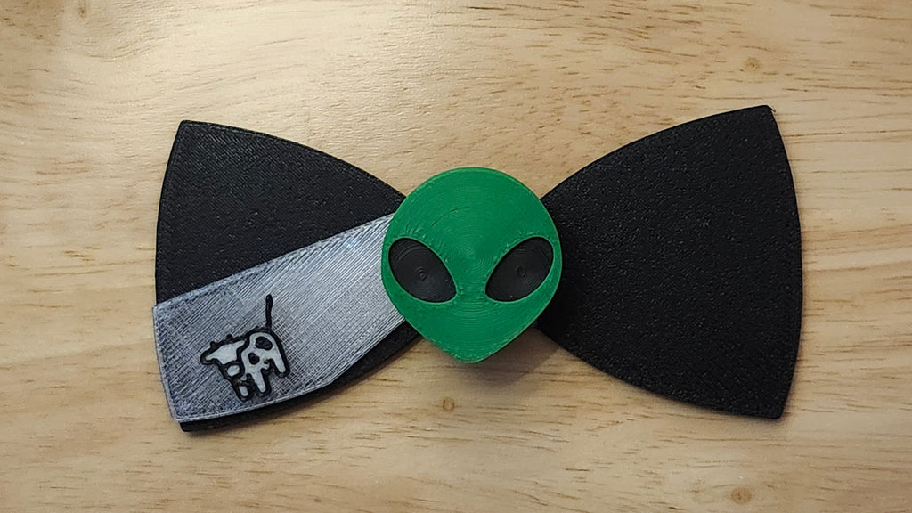 Alien Head Button Cover with Alien Peace Hand Bow(reverse side shown) and Cow Beaming Back. 3D printed for use as a bow tie, button cover, necklace, pin, hat pin, lapel pin and so much more.