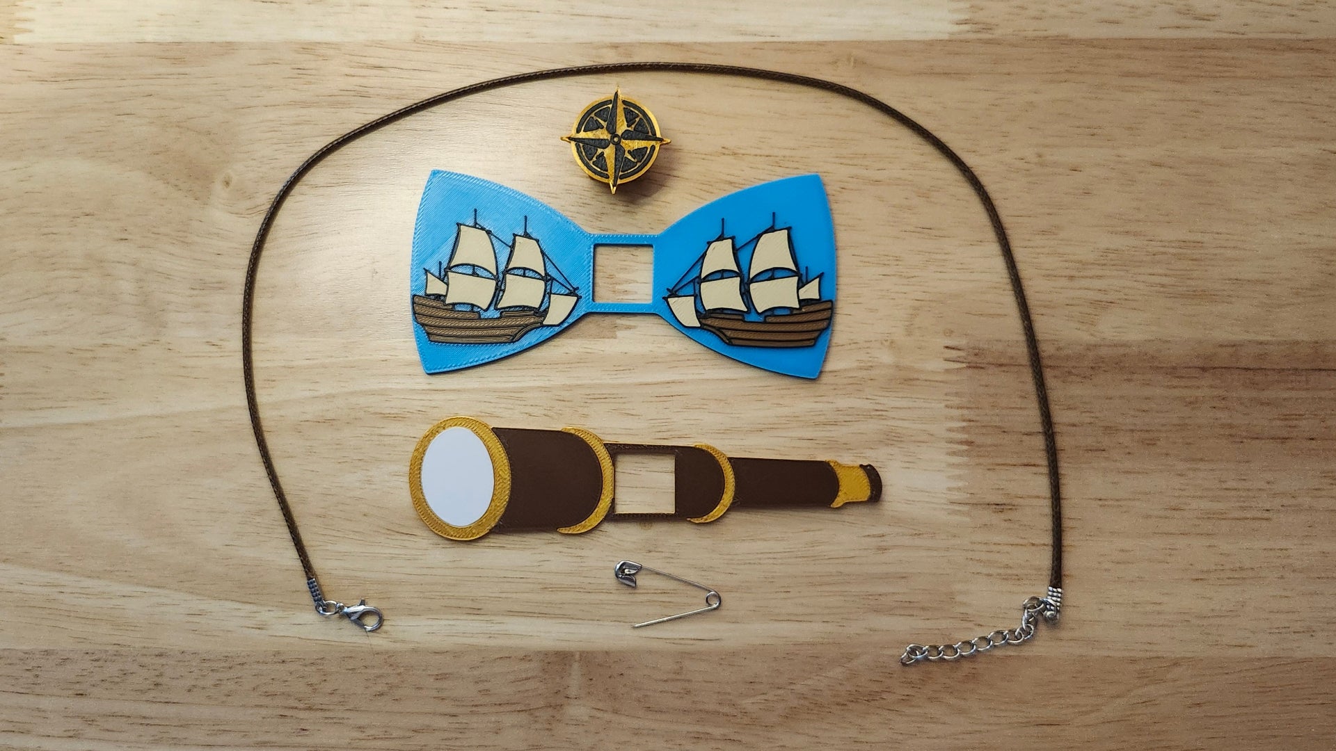 Pirate Ship Bundle including the Compass Button Cover, Ship Bow, Spyglass Back, a safety pin and an 18 inch brown necklace. 3D printed for use as a bow tie, button cover, necklace, pin, hat pin, lapel pin and so much more.
